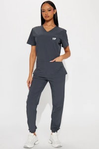 a woman wearing a grey scrub suit with a v - neck and pockets